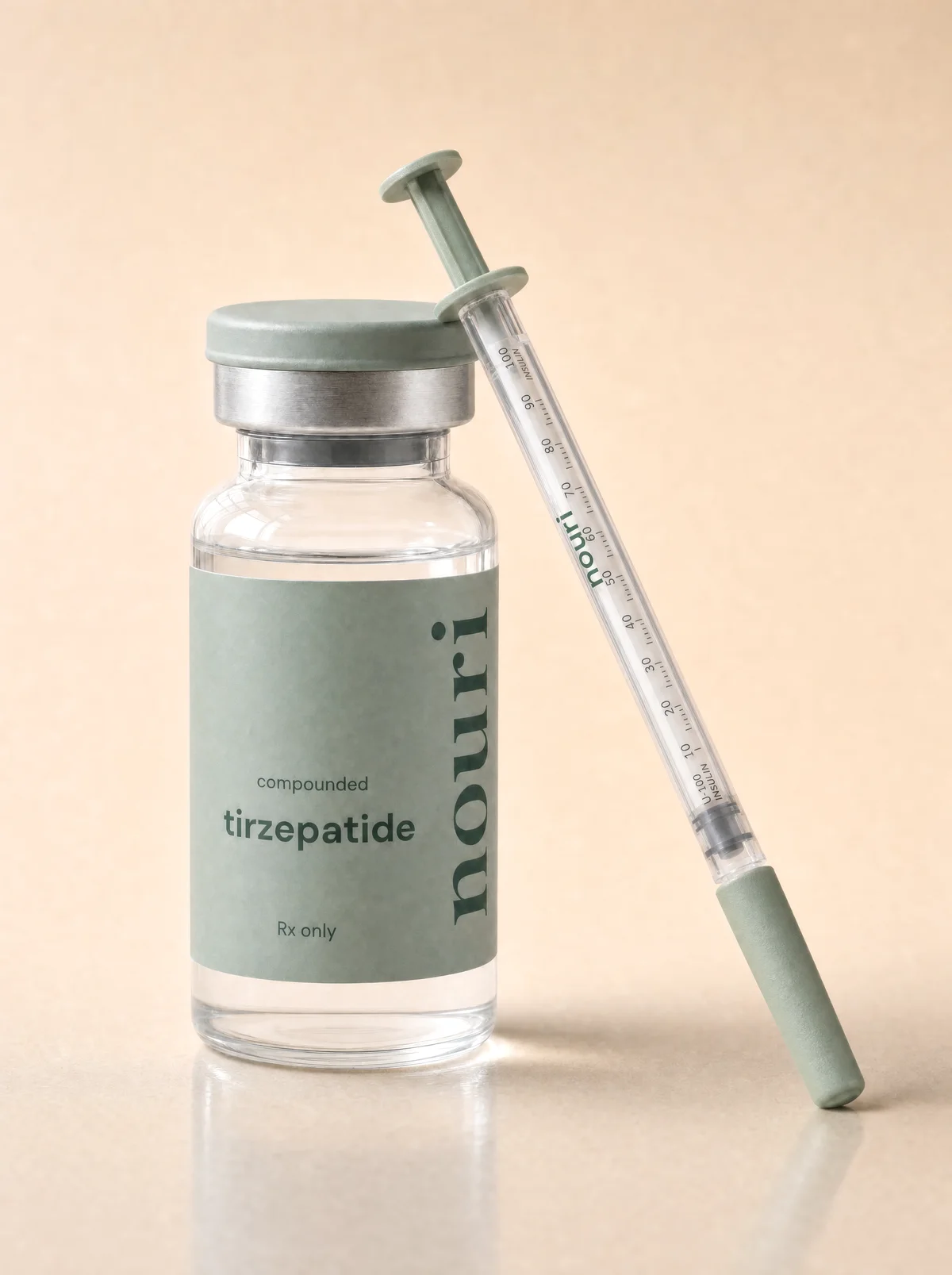 A vial of compounded tirzepatide beside a pre-filled insulin syringe on a warm beige surface